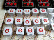 Multiple white cubes with 'SOS' buttons on a circuit board with red LED displays.