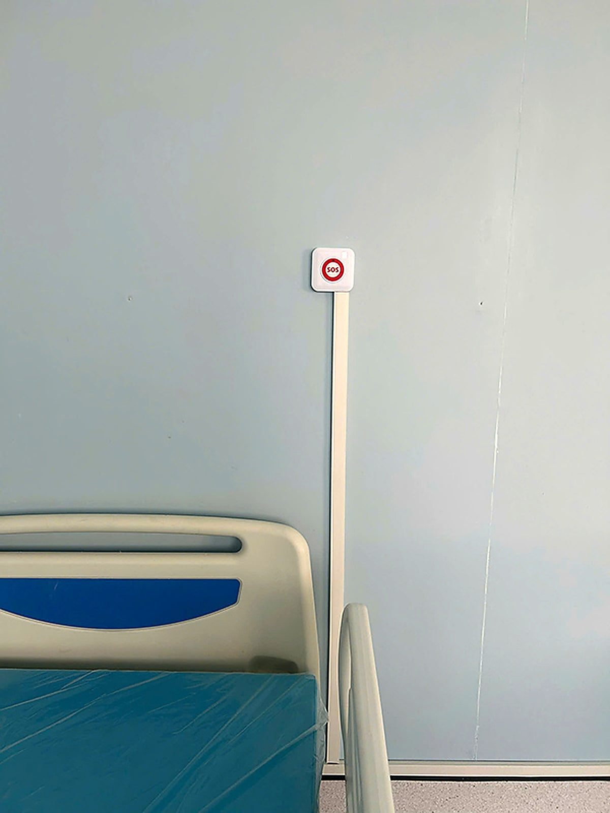 Bed with blue mattress against a light gray wall