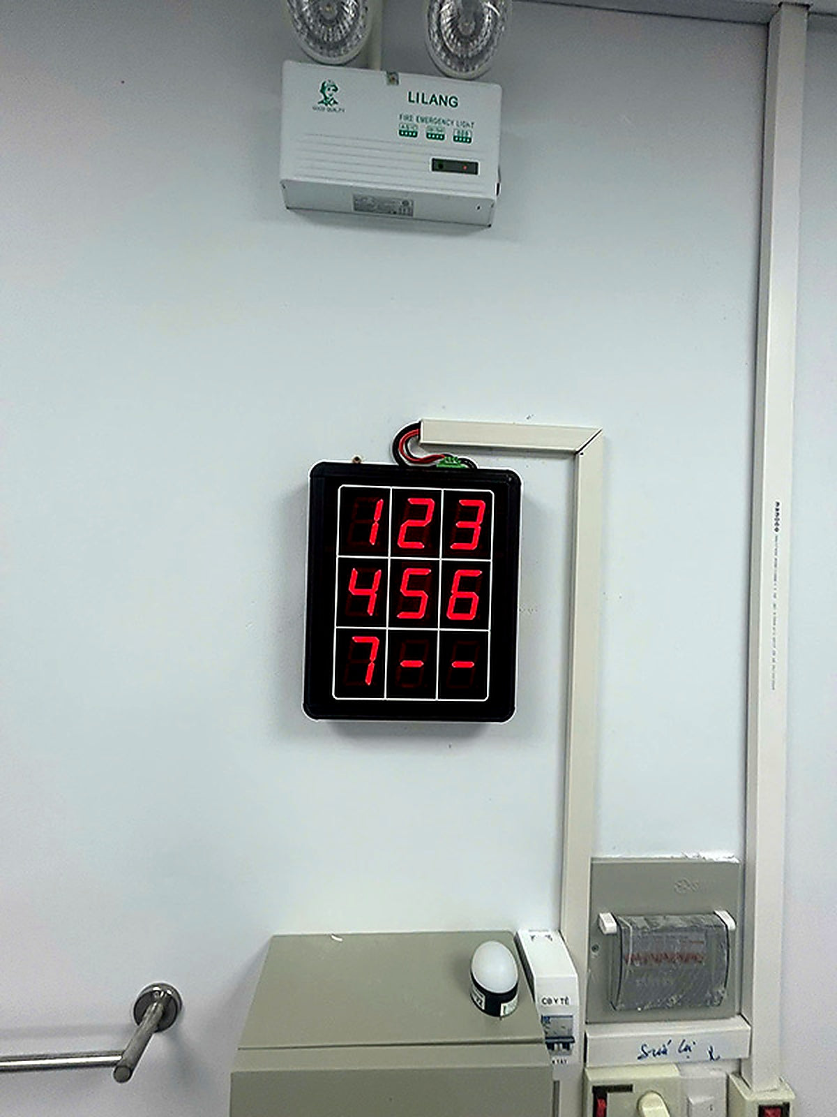Digital display with red LED numbers on a white wall.