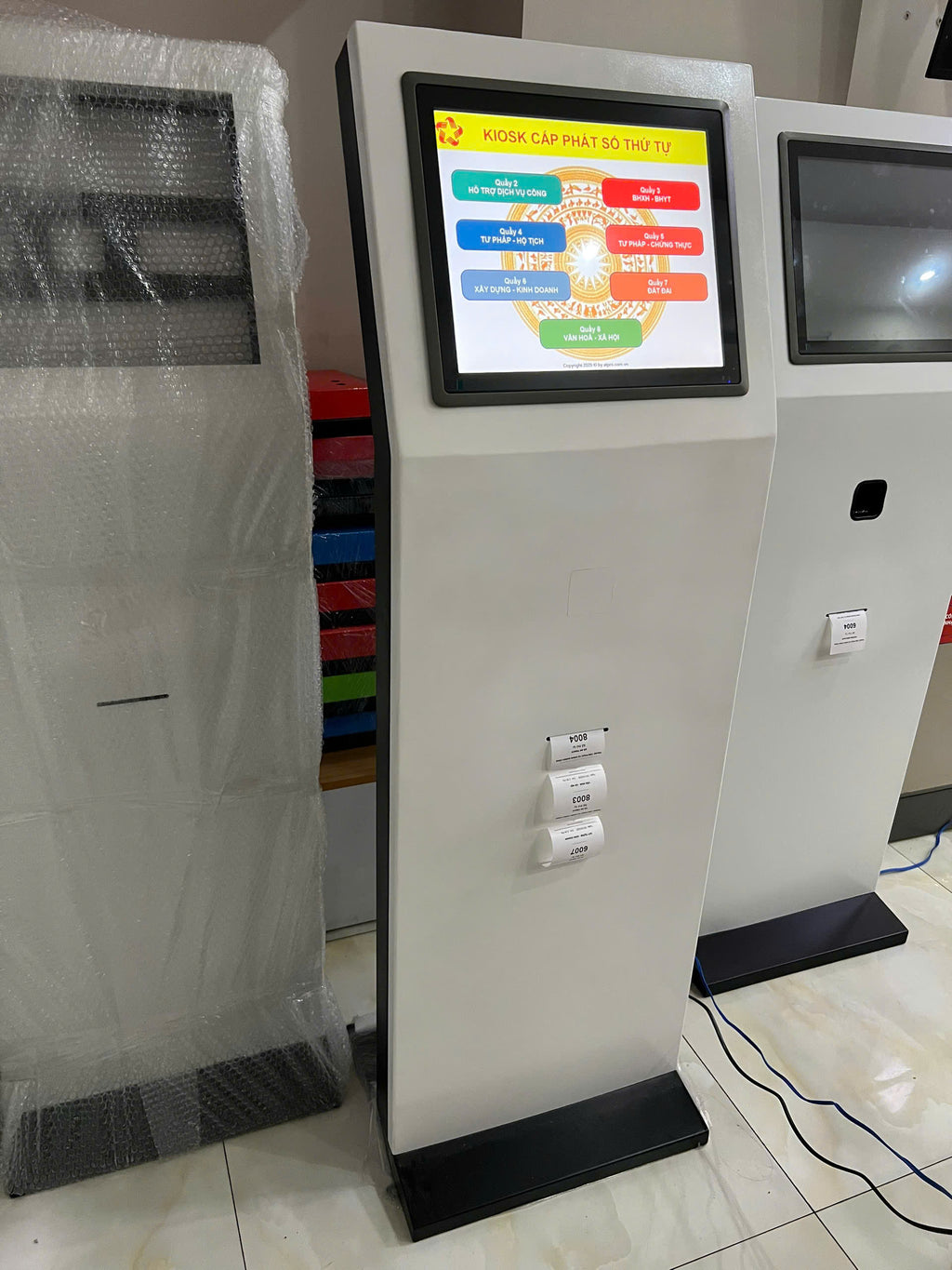 Tall electronic kiosk with a colorful display screen on a tiled floor.