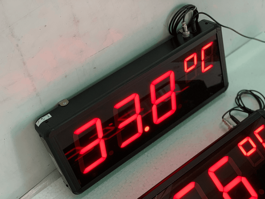 Digital temperature display with red LED numbers on a white wall.
