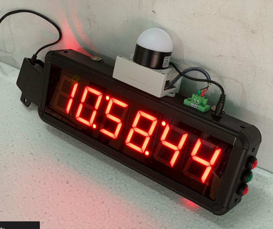 Digital clock with red LED display on a white surface
