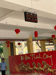 Digital clock on a ceiling with red lanterns and a decorative banner featuring horses.