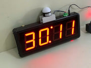 Digital clock with red LED display on a white surface
