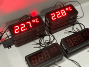 Digital temperature displays with red LED readings on a white surface.