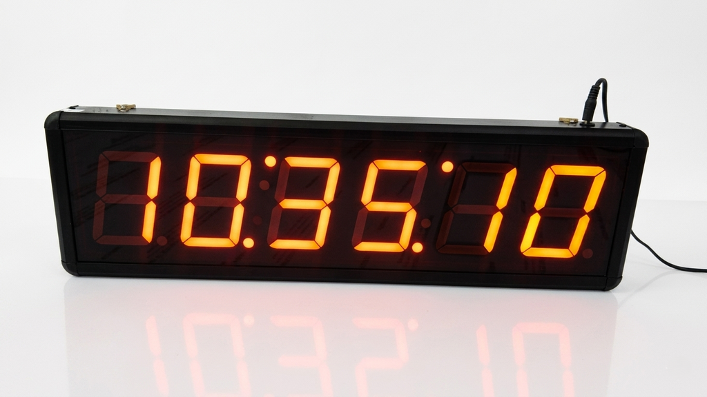 Digital clock with orange LED display on a white background