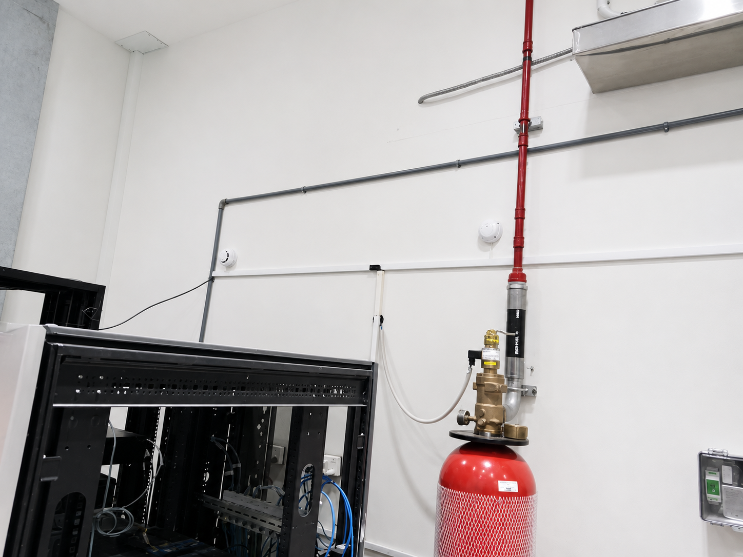 Fire extinguisher mounted on a wall next to a piece of electronic equipment.