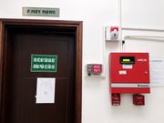 Fire alarm system on a wall next to a door with signs and notices.