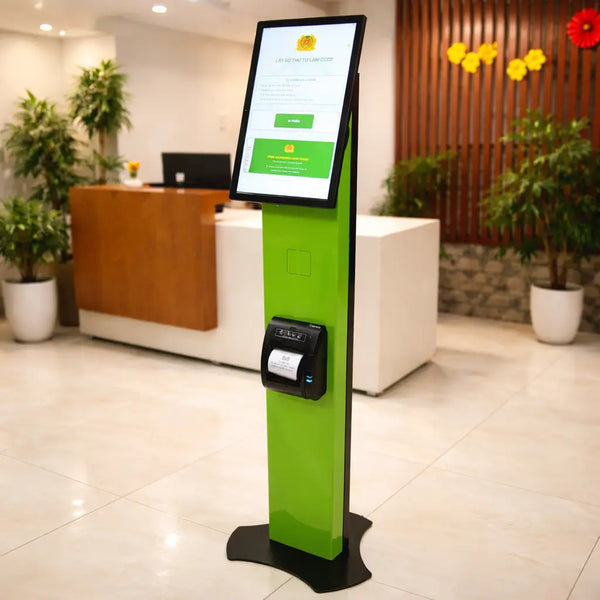 A sleek green self-service kiosk with a touchscreen and printer in a bright office lobby, used for administrative queue management.