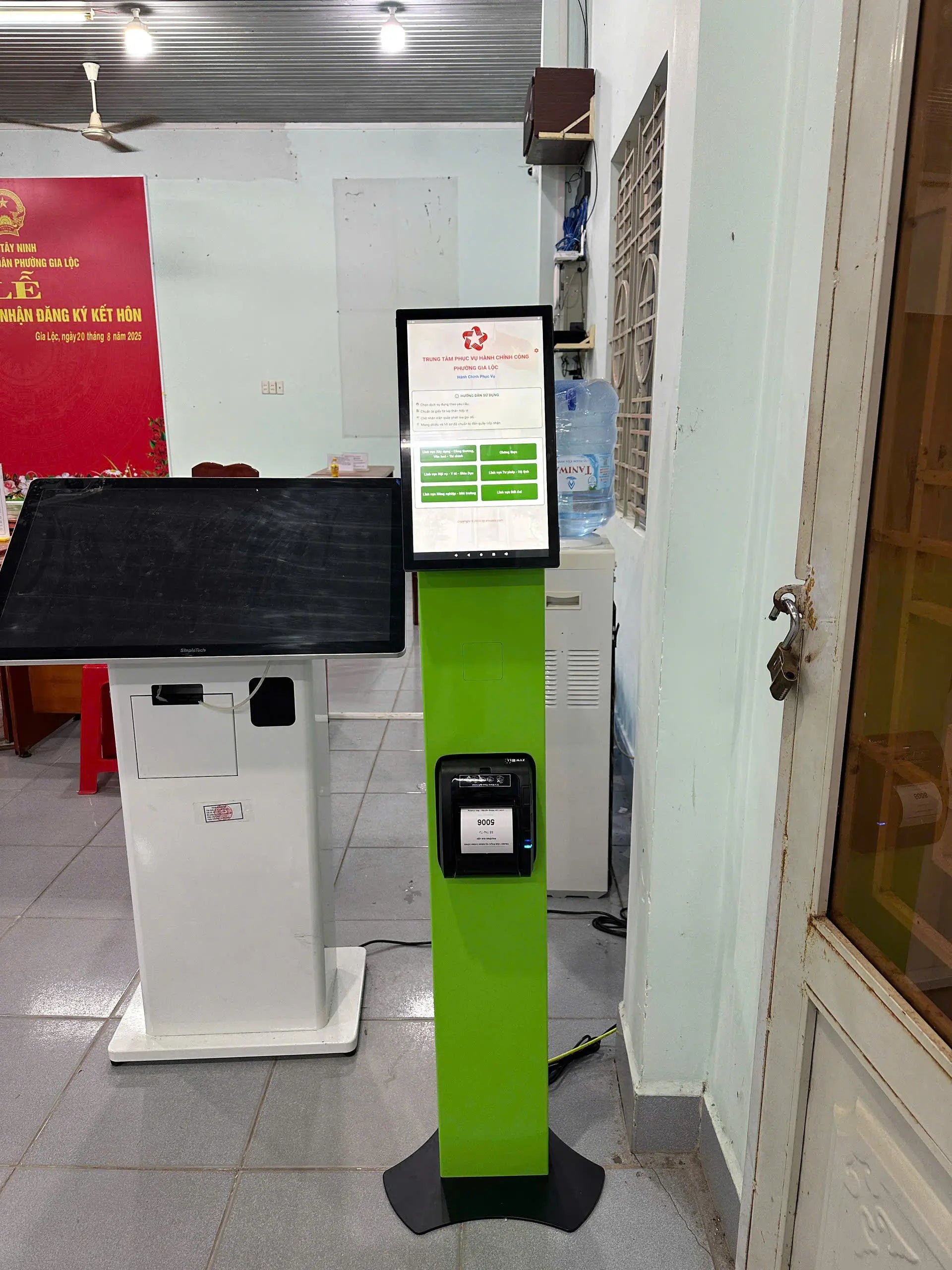 Green and white interactive kiosk with a screen in an indoor setting.