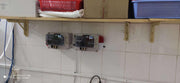 Control panels on a tiled wall with shelves above