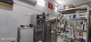 Drugstore interior with shelves stocked with medications, a refrigerator, and a Vietnamese flag on the wall.