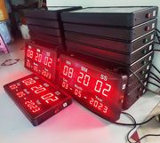 Stack of digital clocks with red LED display on a white surface.