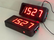 Two digital clocks with red LED display on a white surface