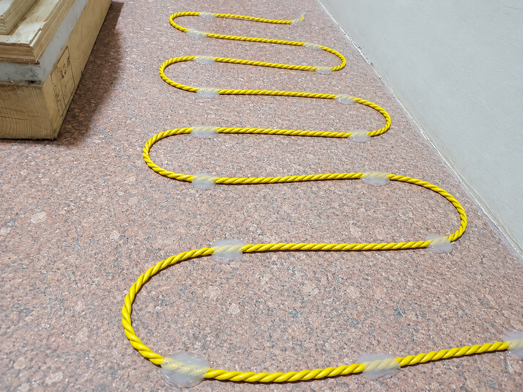 Yellow safety rope with reflective markers on a concrete surface