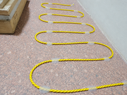 Yellow safety rope with reflective markers on a concrete surface