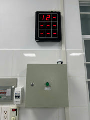 Digital clock displaying the time '12' on a tiled wall.