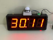 Digital clock with red LED display on a white surface